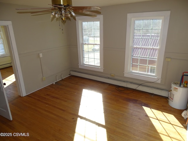 unfurnished dining area featuring wood-type flooring, baseboard heating, ceiling fan, and a healthy amount of sunlight