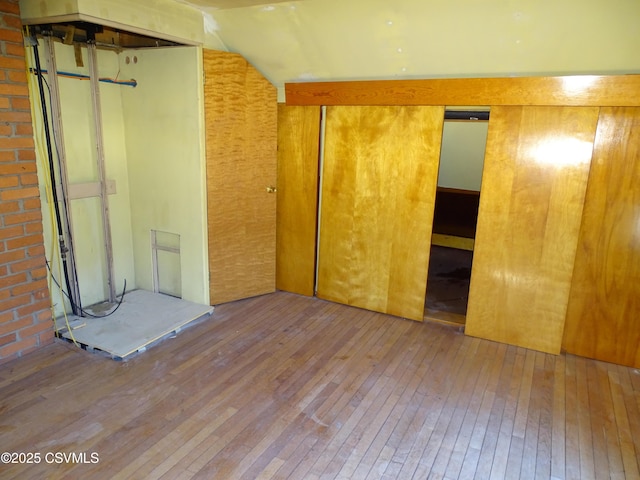 unfurnished bedroom with lofted ceiling, wood-type flooring, and a closet