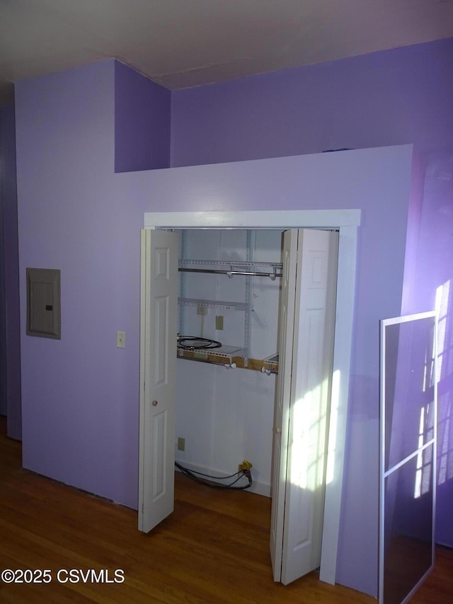 unfurnished bedroom featuring hardwood / wood-style flooring, electric panel, and a closet