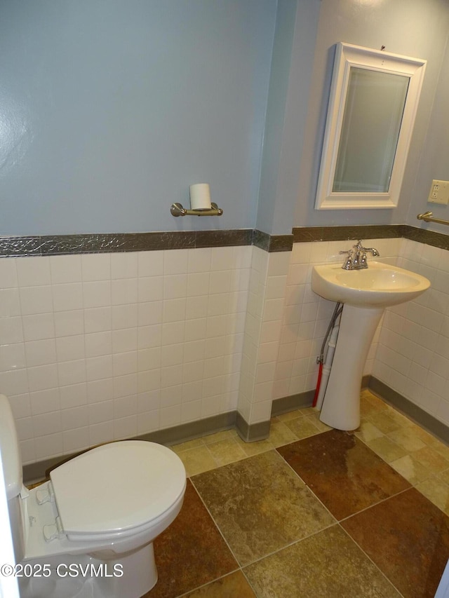 bathroom with sink, tile walls, and toilet