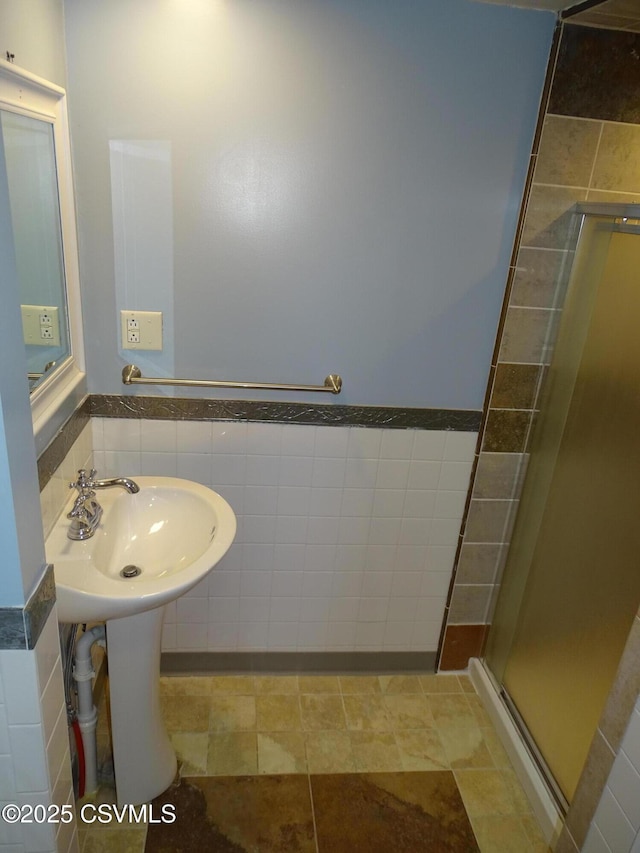 bathroom featuring tile patterned flooring, a shower with door, tile walls, and sink