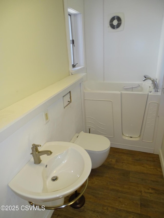 bathroom featuring a bathing tub, toilet, wood-type flooring, and sink