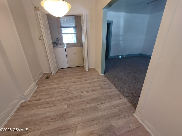 hallway featuring light hardwood / wood-style floors and separate washer and dryer