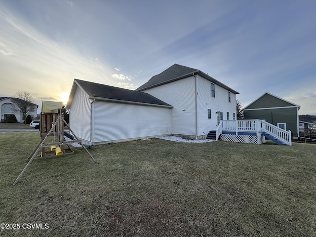 property exterior at dusk featuring a lawn and a wooden deck