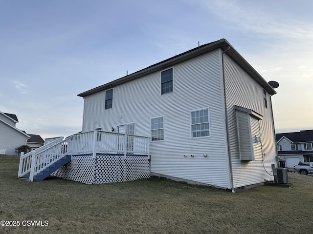 back house at dusk featuring central AC, a yard, and a deck