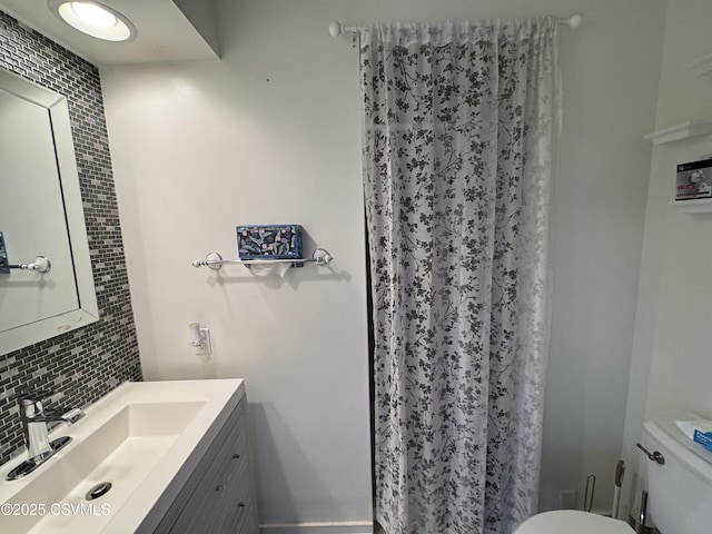 bathroom featuring vanity, backsplash, and toilet