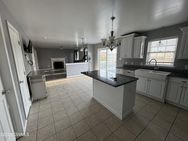 kitchen featuring white cabinets, a kitchen island, a wealth of natural light, and light tile patterned flooring