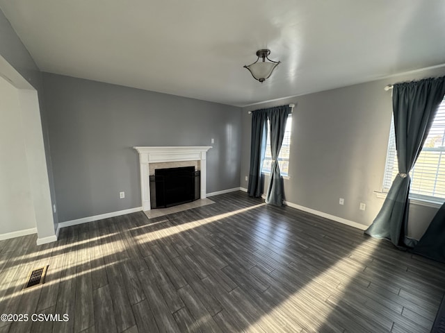 unfurnished living room with plenty of natural light and dark hardwood / wood-style flooring