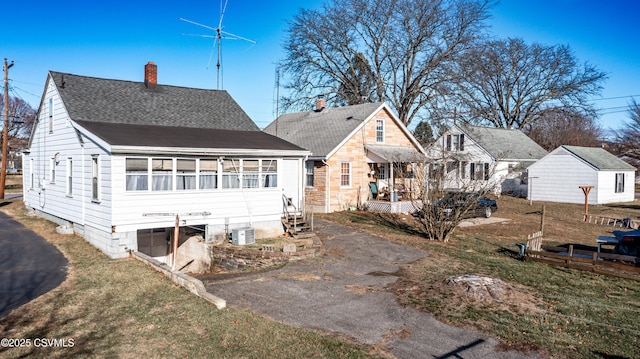 back of property with central AC unit, a garage, and a lawn