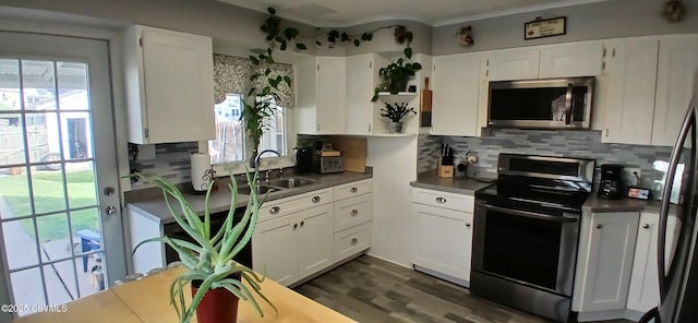 kitchen with backsplash, stainless steel appliances, white cabinetry, and sink