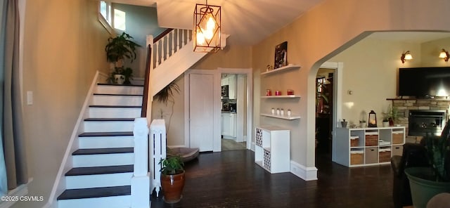 stairway with hardwood / wood-style floors and a stone fireplace