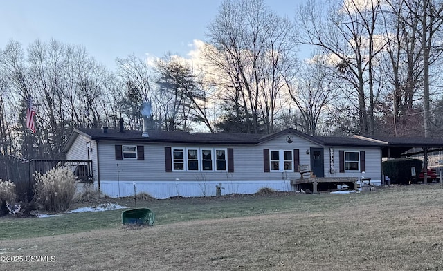 manufactured / mobile home with a front lawn and a carport