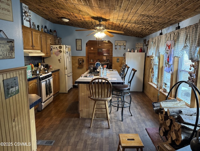 kitchen featuring wood ceiling, white appliances, ceiling fan, a kitchen island with sink, and dark hardwood / wood-style floors