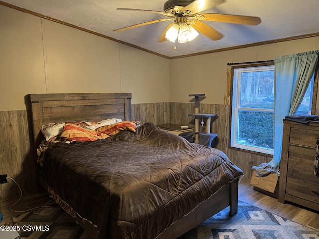 bedroom with crown molding, ceiling fan, wood-type flooring, and multiple windows