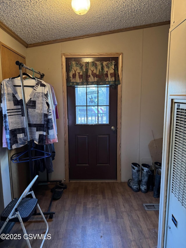 interior space with dark wood-type flooring, ornamental molding, and a textured ceiling