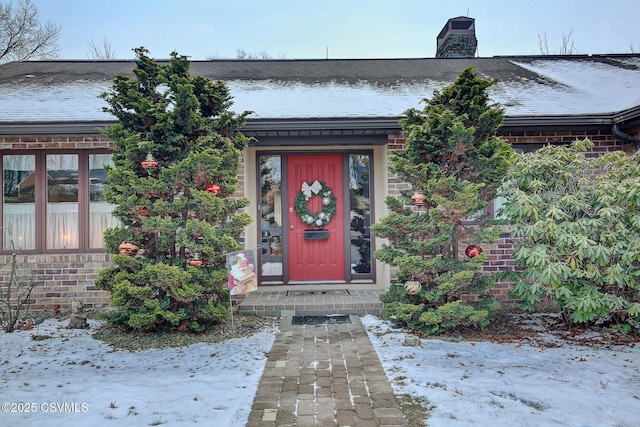 property entrance featuring brick siding and a chimney