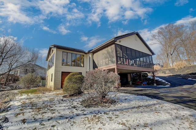 view of front of home with aphalt driveway and a sunroom