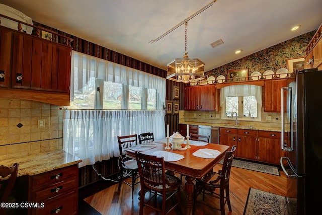 dining area featuring a chandelier, lofted ceiling, visible vents, and light wood finished floors