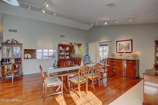 dining room with lofted ceiling, visible vents, and wood finished floors