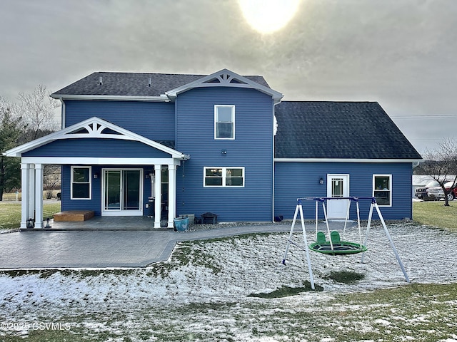 snow covered rear of property featuring a playground and a patio