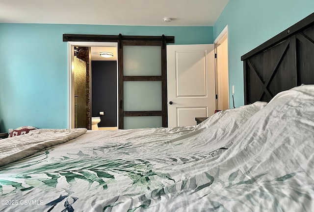 bedroom featuring a barn door and ensuite bath