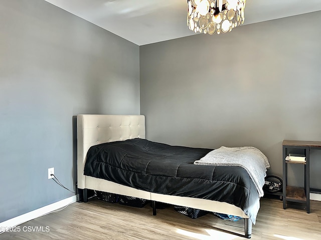 bedroom with light wood-type flooring and a notable chandelier