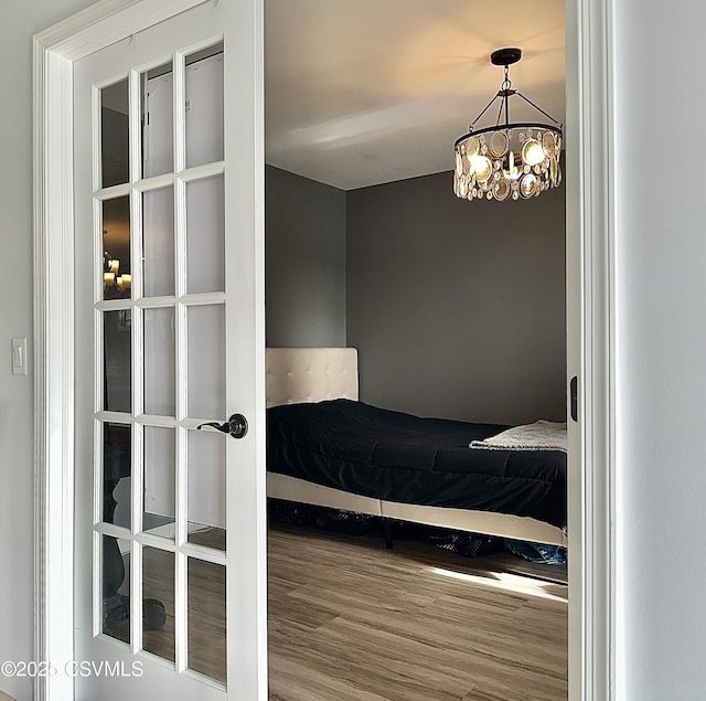 bedroom with hardwood / wood-style floors and a notable chandelier