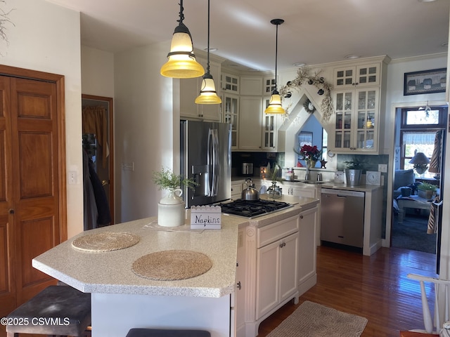 kitchen featuring a kitchen breakfast bar, tasteful backsplash, stainless steel appliances, decorative light fixtures, and a center island