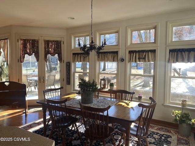 dining space with hardwood / wood-style floors, plenty of natural light, french doors, and a chandelier