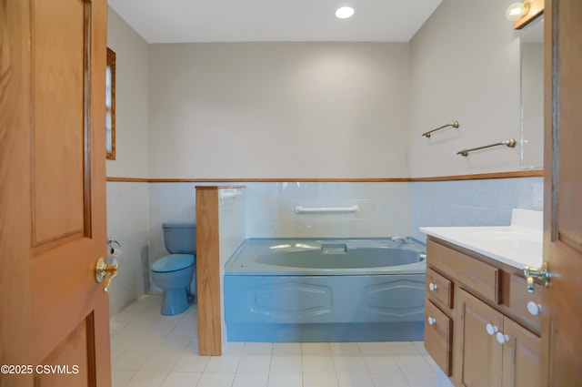 bathroom with a tub, vanity, tile walls, and toilet