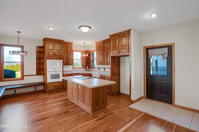 kitchen featuring pendant lighting, white appliances, a center island, and light hardwood / wood-style flooring