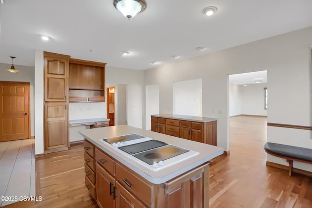 kitchen with pendant lighting, light hardwood / wood-style floors, stovetop, and a center island