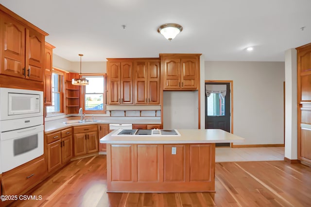 kitchen with hanging light fixtures, white appliances, light hardwood / wood-style floors, and a kitchen island