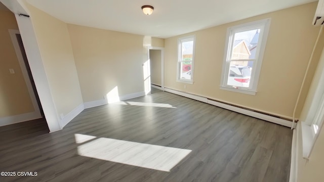 spare room with baseboard heating and dark wood-type flooring