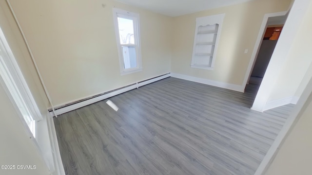 empty room featuring a wealth of natural light, built in features, light hardwood / wood-style flooring, and a baseboard radiator