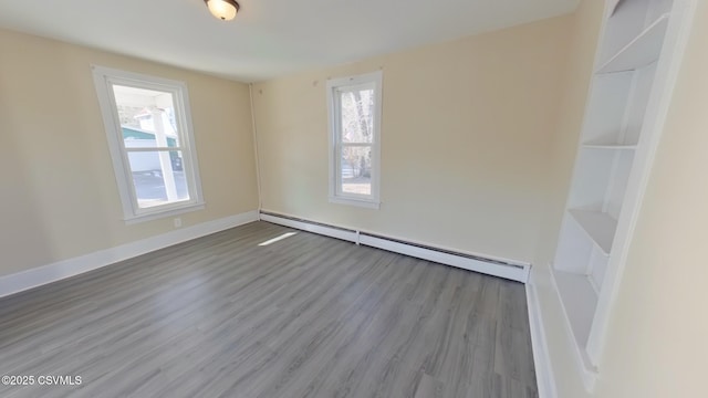 empty room with baseboard heating and light hardwood / wood-style floors