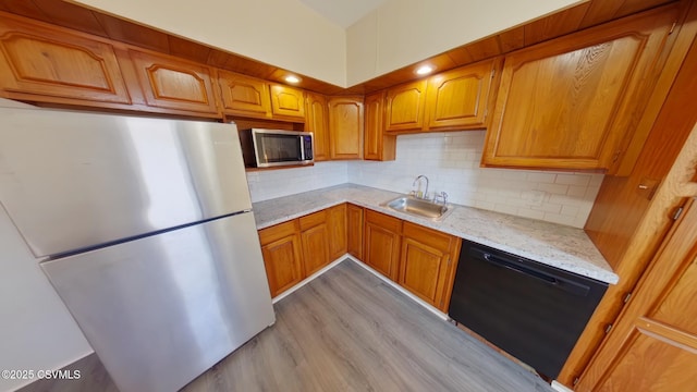 kitchen with tasteful backsplash, light hardwood / wood-style floors, sink, stainless steel appliances, and light stone counters