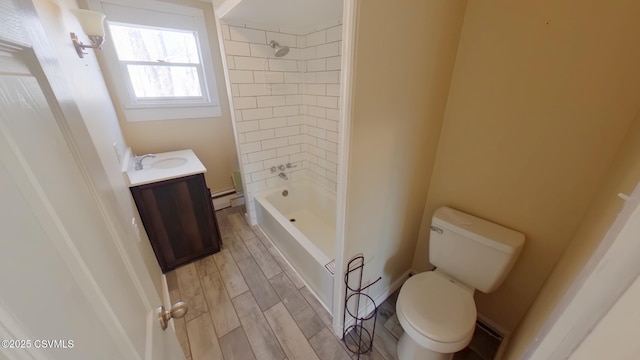 full bathroom with toilet, tiled shower / bath, a baseboard heating unit, and vanity