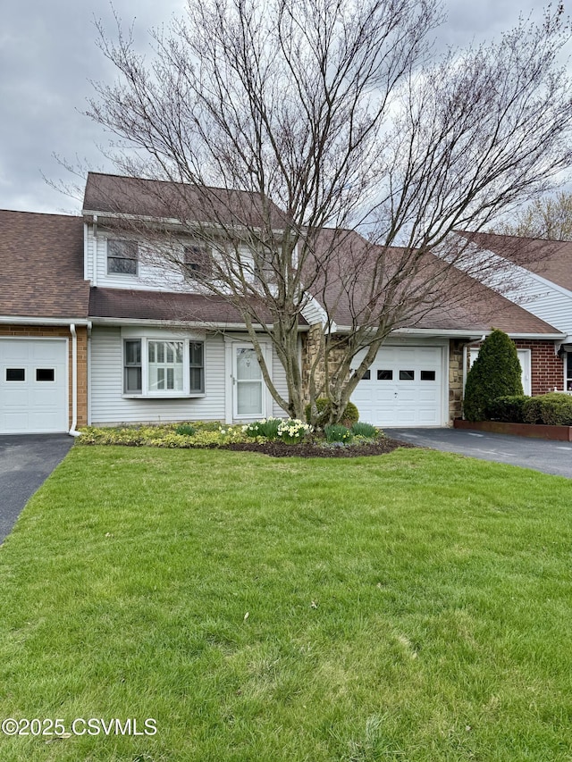 traditional-style home with driveway, an attached garage, and a front lawn