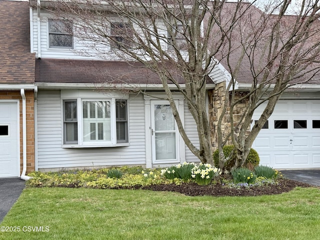 multi unit property with aphalt driveway, a front lawn, and roof with shingles