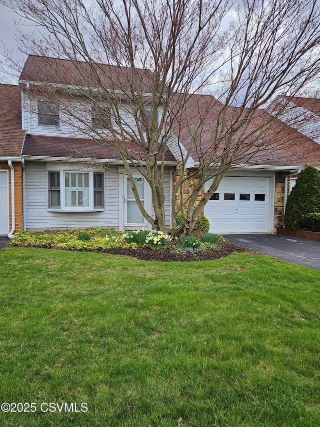 traditional-style house with a front yard, a garage, and aphalt driveway