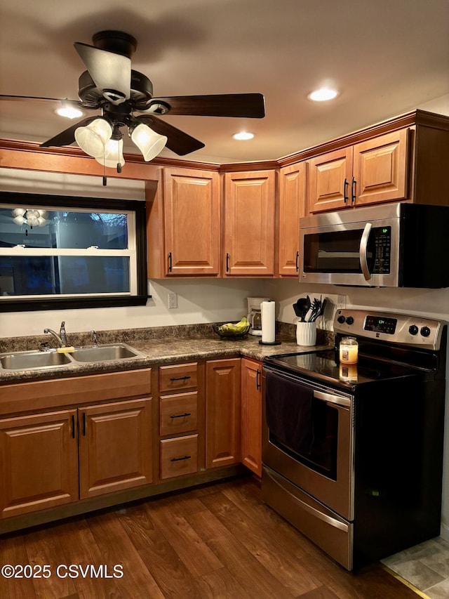 kitchen with ceiling fan, dark wood-type flooring, appliances with stainless steel finishes, and sink