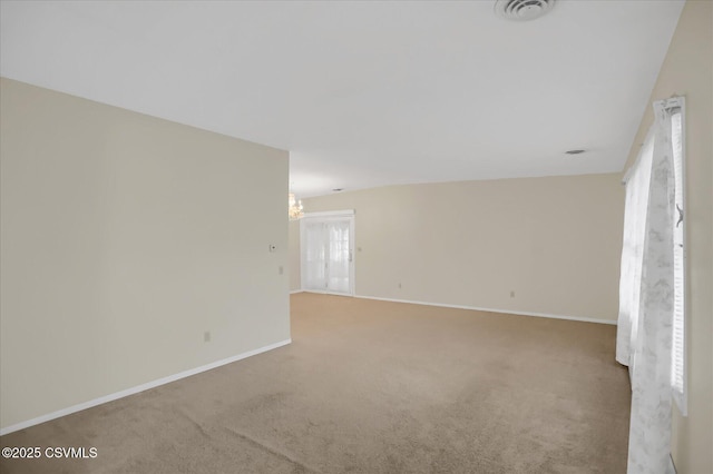 unfurnished room with an inviting chandelier, carpet flooring, and a healthy amount of sunlight