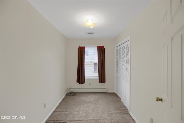 unfurnished bedroom featuring light colored carpet, a closet, and a baseboard heating unit