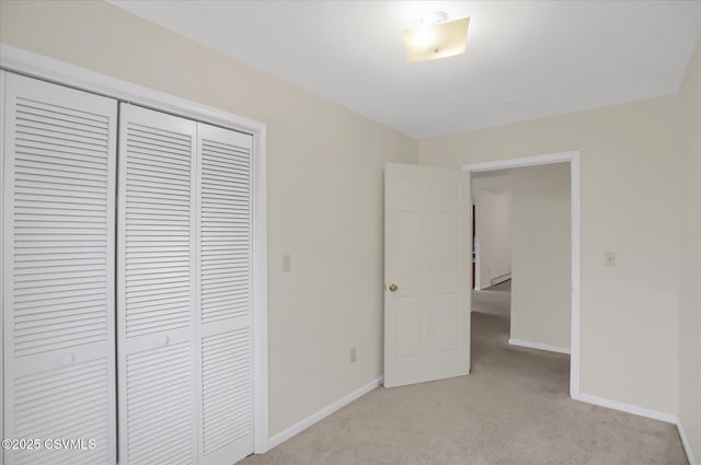 unfurnished bedroom featuring light carpet, a closet, and a baseboard heating unit