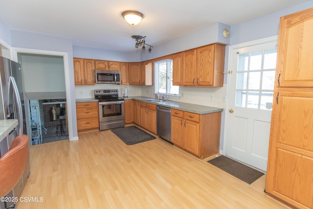 kitchen with sink, light wood-type flooring, decorative backsplash, and stainless steel appliances