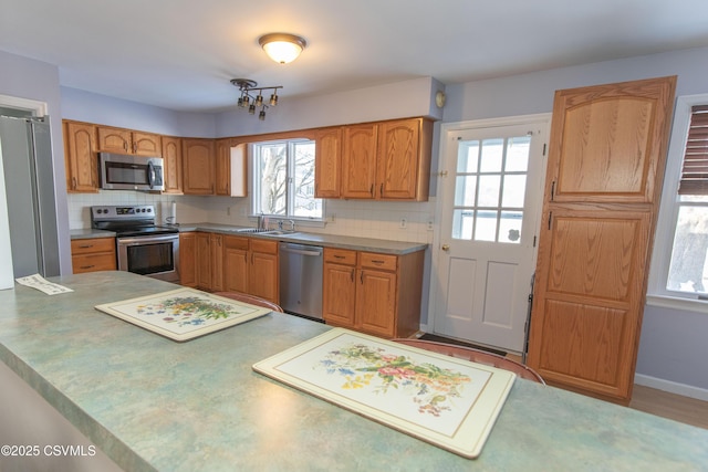 kitchen with kitchen peninsula, backsplash, appliances with stainless steel finishes, and sink