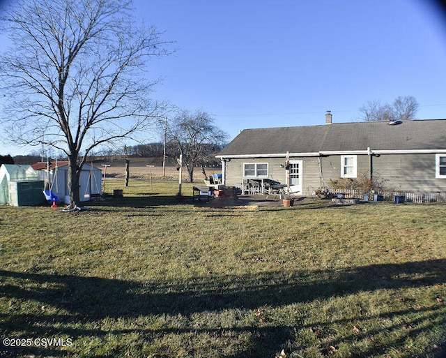 rear view of house featuring a lawn, a storage shed, and a patio area