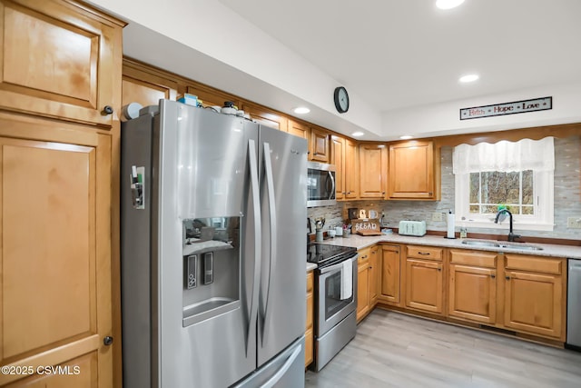 kitchen with light wood-type flooring, backsplash, sink, and stainless steel appliances