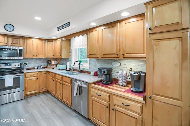 kitchen with sink, light hardwood / wood-style flooring, stainless steel appliances, and tasteful backsplash